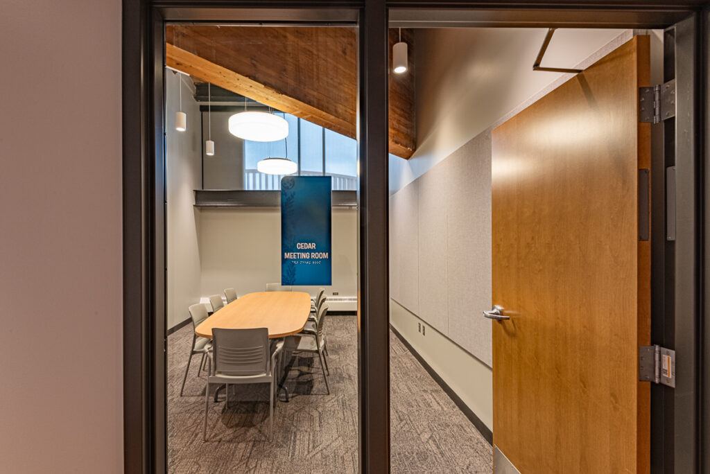 A meeting room with an oval table with office chairs placed around it.