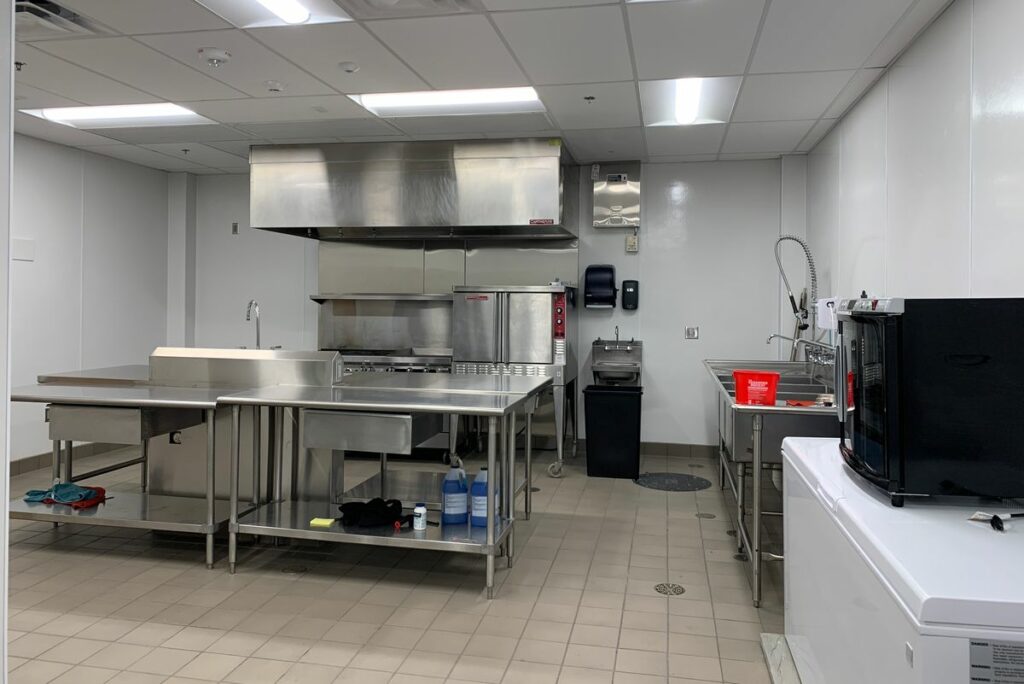 A kitchen with counter, stove, fridge, and sink.