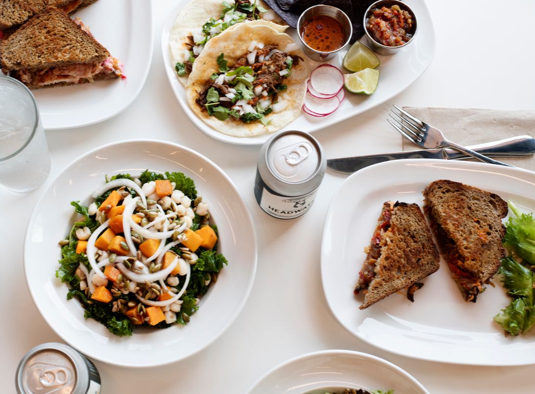 A table with sandwiches, salads, and tacos.