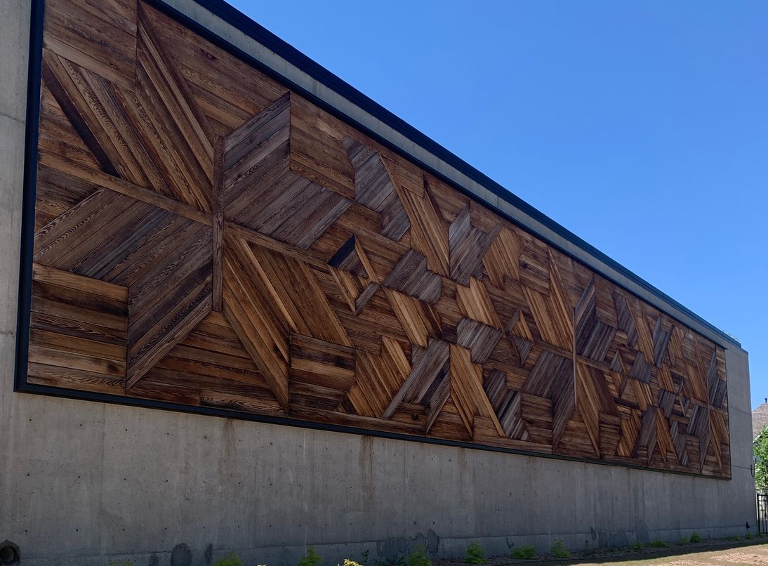 A giant mural made of cedar pieces that are arranged to look like a feather turning in space.